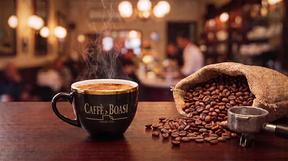 Czarna filiżanka Caffe Boasi w kawiarnianym otoczeniu z rozsypanym ziarnem